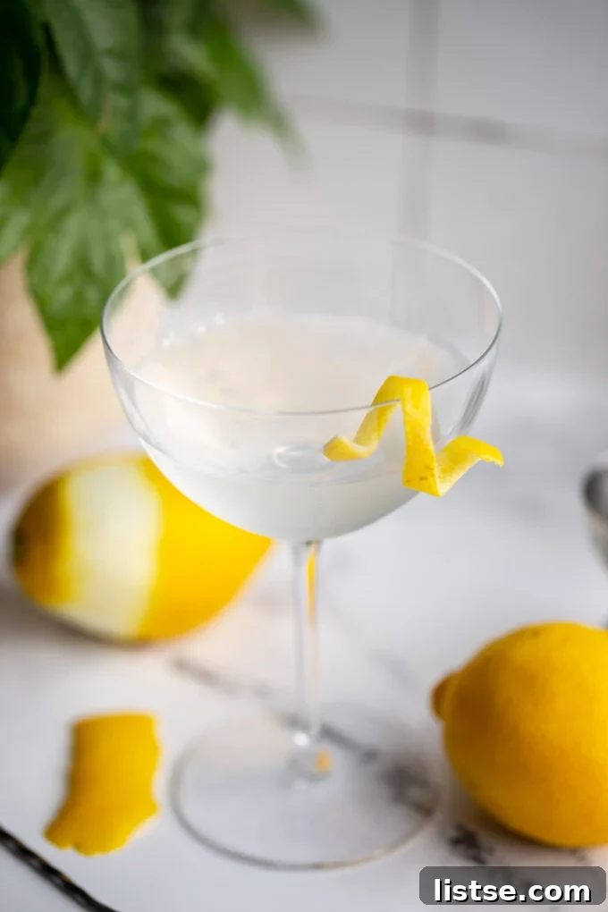 A close-up of a meticulously prepared Vesper cocktail, adorned with a perfectly curled lemon twist, resting on a sophisticated bar top, ready for indulgence.
