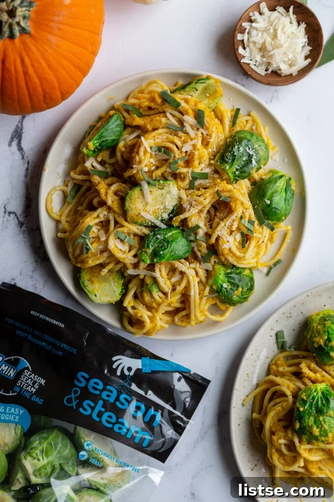 A visually appealing shot of creamy pumpkin pasta spaghetti served on a plate, adorned with vibrant Brussels sprouts. Small, autumnal pumpkins are decoratively placed in the corner of the image, while a branded bag of Ocean Mist Farms sprouts is visible, emphasizing the key ingredient.