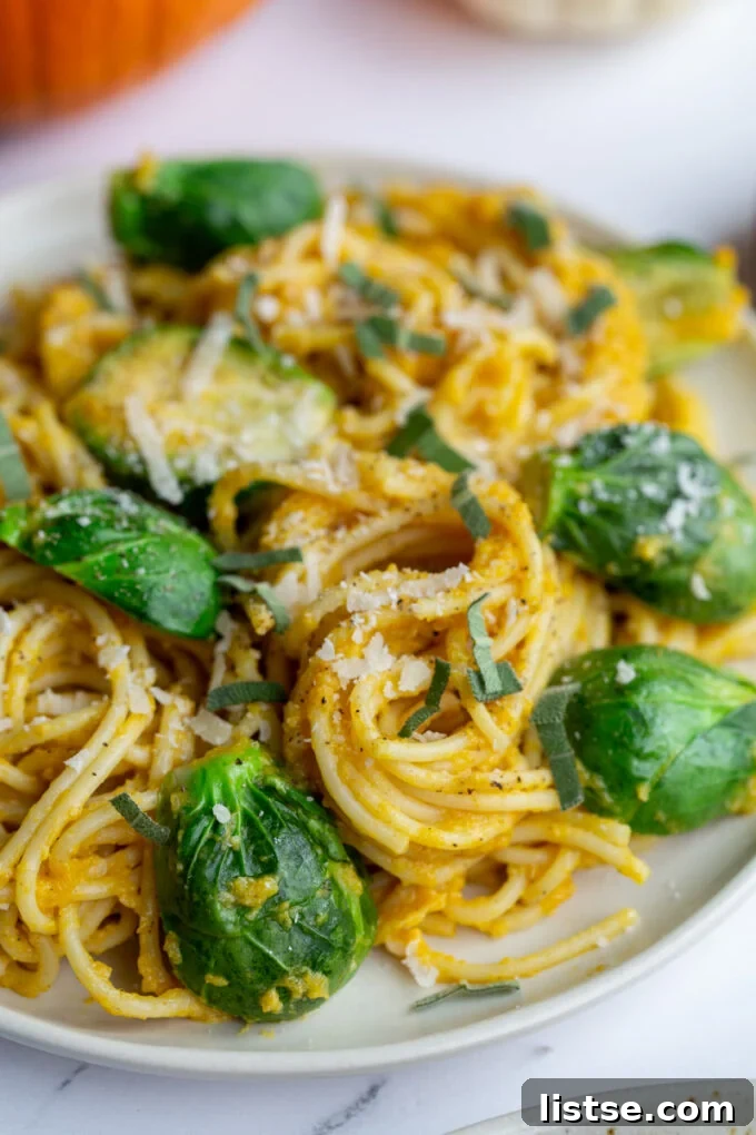 A mouth-watering image of creamy pumpkin pasta spaghetti presented on a plate, elegantly topped with steamed Brussels sprouts, ready to be enjoyed.