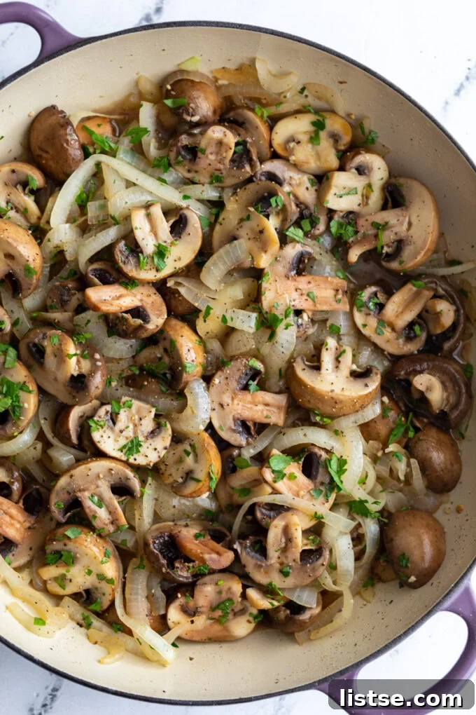 Large skillet filled with beautifully sautéed mushrooms and onions, garnished with fresh herbs