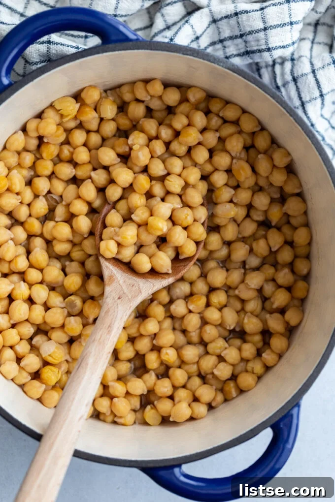 Big pot of perfectly cooked chickpeas with a wooden spoon resting on the side