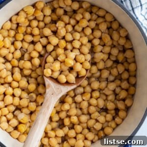 Big pot of cooked chickpeas with a wooden spoon on the side