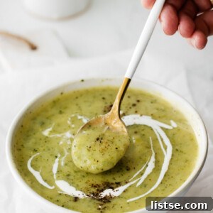 using a spoon to scoop up vegan zucchini soup out of a bowl
