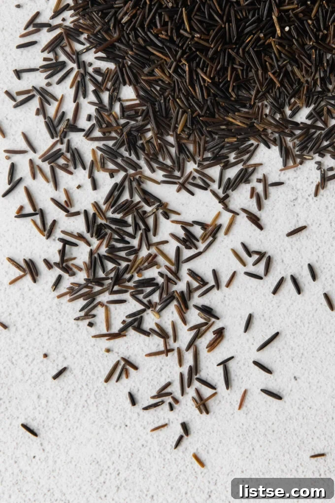A close-up view of uncooked wild rice kernels, showcasing their dark, elongated appearance before cooking.