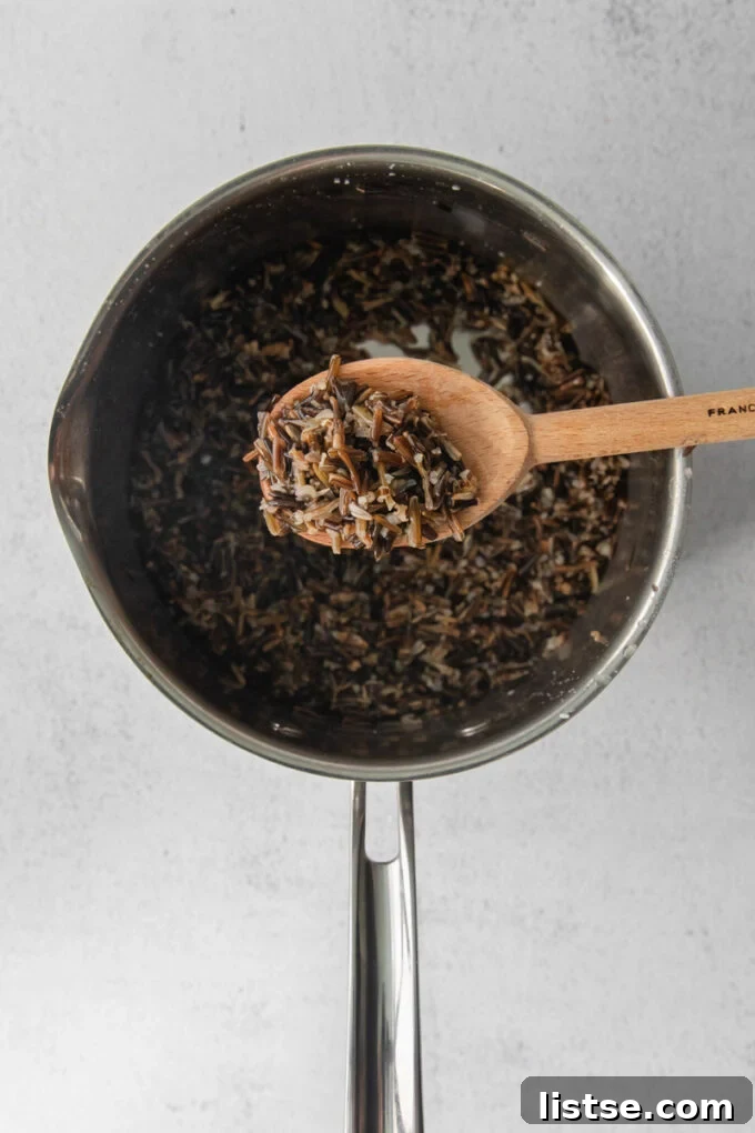 Serving freshly cooked wild rice from a pot using a wooden spoon, highlighting its texture.