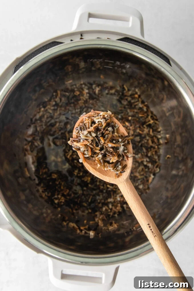 Spoonfuls of wild rice being scooped out of an Instant Pot, showing its separate grains.