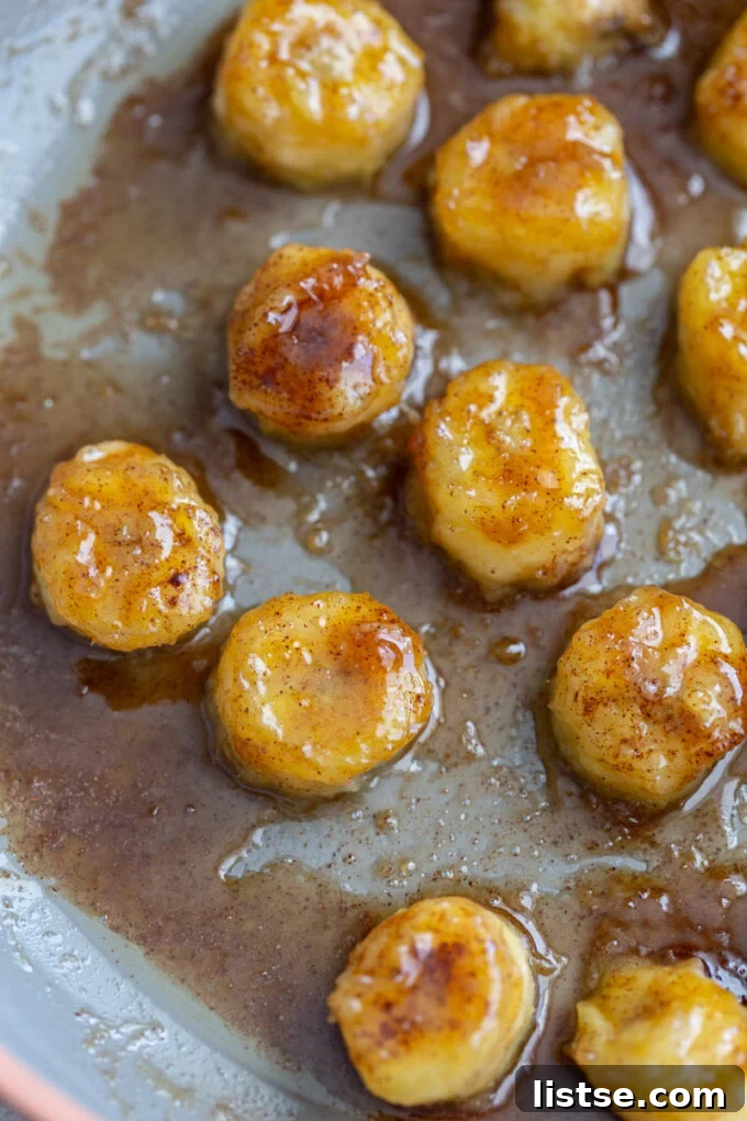 Molten Caramel Bananas 3 Caramelized bananas cooking in a skillet, turning golden brown.