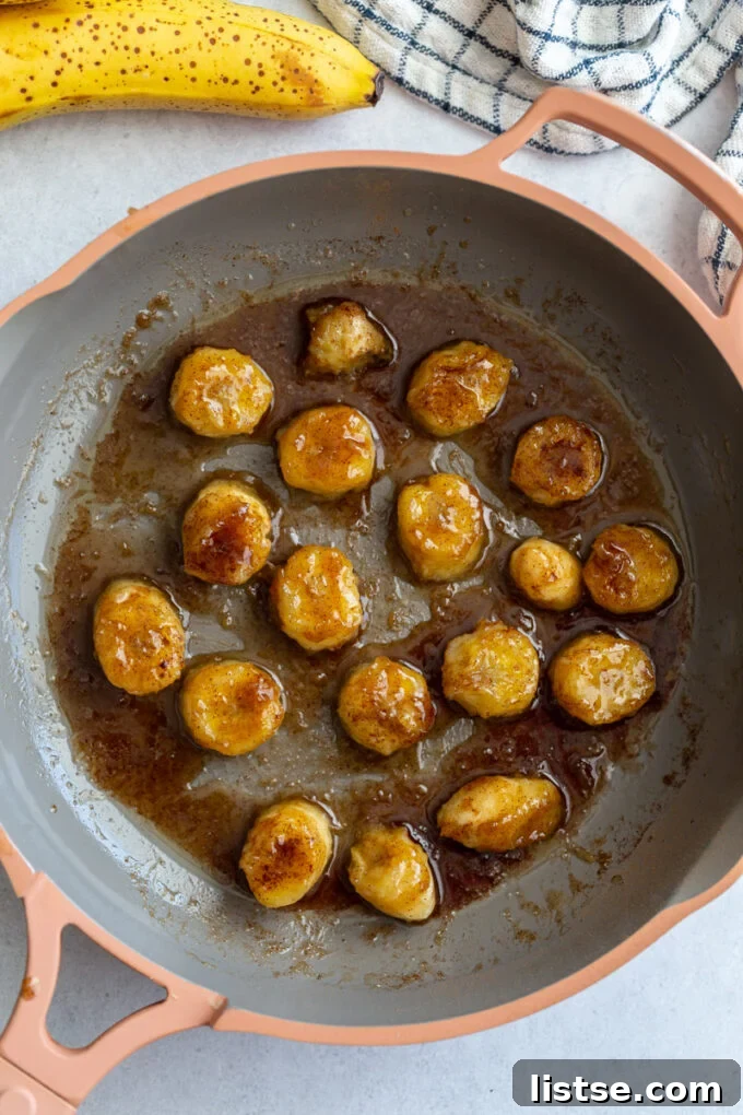 Molten Caramel Bananas 4 Pan-fried bananas cooking in a skillet, coated in brown sugar and cinnamon.
