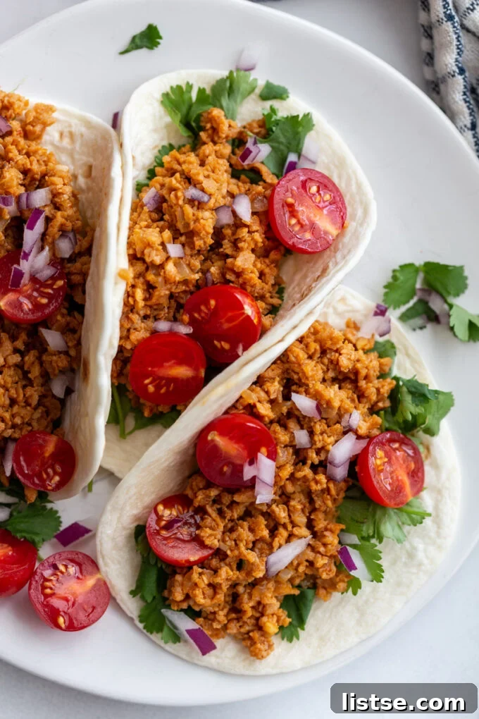 Unlocking TVP: A Comprehensive Guide to Versatile Plant-Based Meals and Perfect Tacos 2 Three TVP tacos on a plate, garnished with fresh cilantro, vibrant cherry tomatoes, and diced red onion, highlighting a flavorful plant-based meal