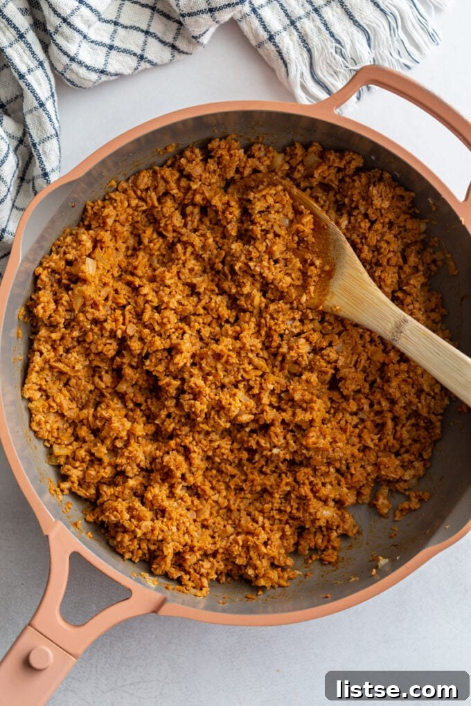 Unlocking TVP: A Comprehensive Guide to Versatile Plant-Based Meals and Perfect Tacos 6 Seasoned TVP taco meat simmering in a vibrant pink skillet, with a wooden spoon resting inside, ready to be served