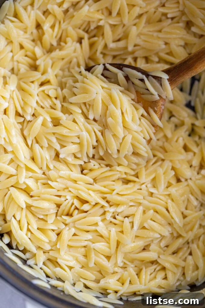 Stirring orzo pasta with a wooden spoon in a pan