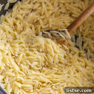 Stirring cooked orzo with a wooden spoon