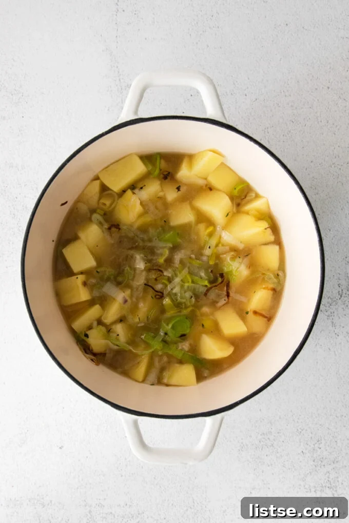 Diced potatoes simmering gently in vegetable stock within a large pot, absorbing flavors.