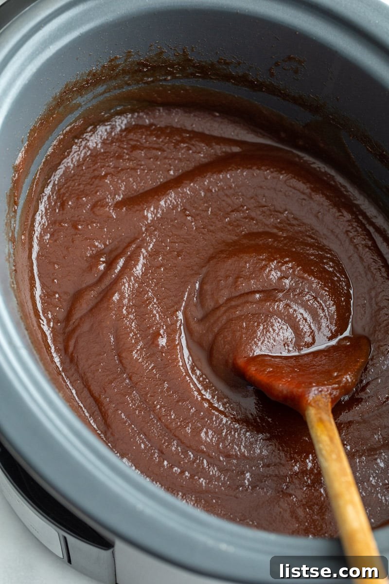apple butter in a crockpot with a wooden spoon in the side