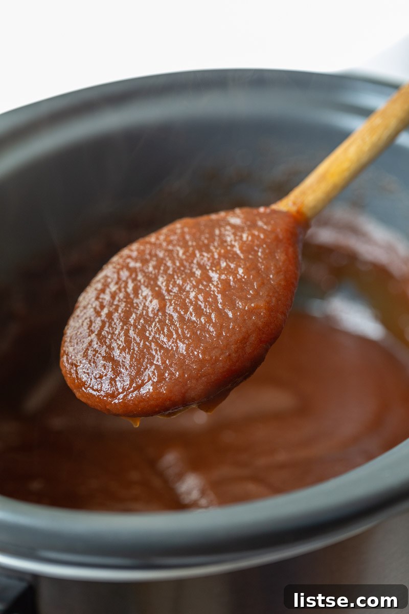 apple butter in a slow cooker with a spoonful being held up to the camera