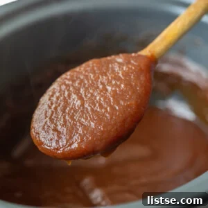 apple butter in a slow cooker with a spoonful being held up to the camera