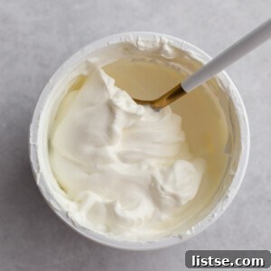 top down shot of a tub of sour cream with a spoon swirled in it