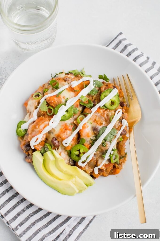 Effortless Vegetarian Crockpot Feasts 14 Cheesy Mexican quinoa casserole, served in a white bowl and garnished with sliced avocado.