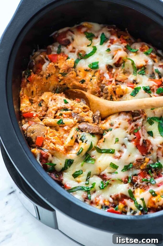 Effortless Vegetarian Crockpot Feasts 16 Close-up of a wooden spoon dishing out cheesy crockpot pasta, showing its rich texture.