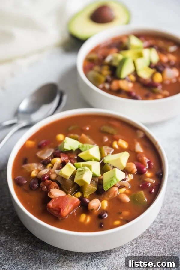 Effortless Vegetarian Crockpot Feasts 6 Hearty vegan crockpot chili, generously topped with diced avocado, served in a white bowl.