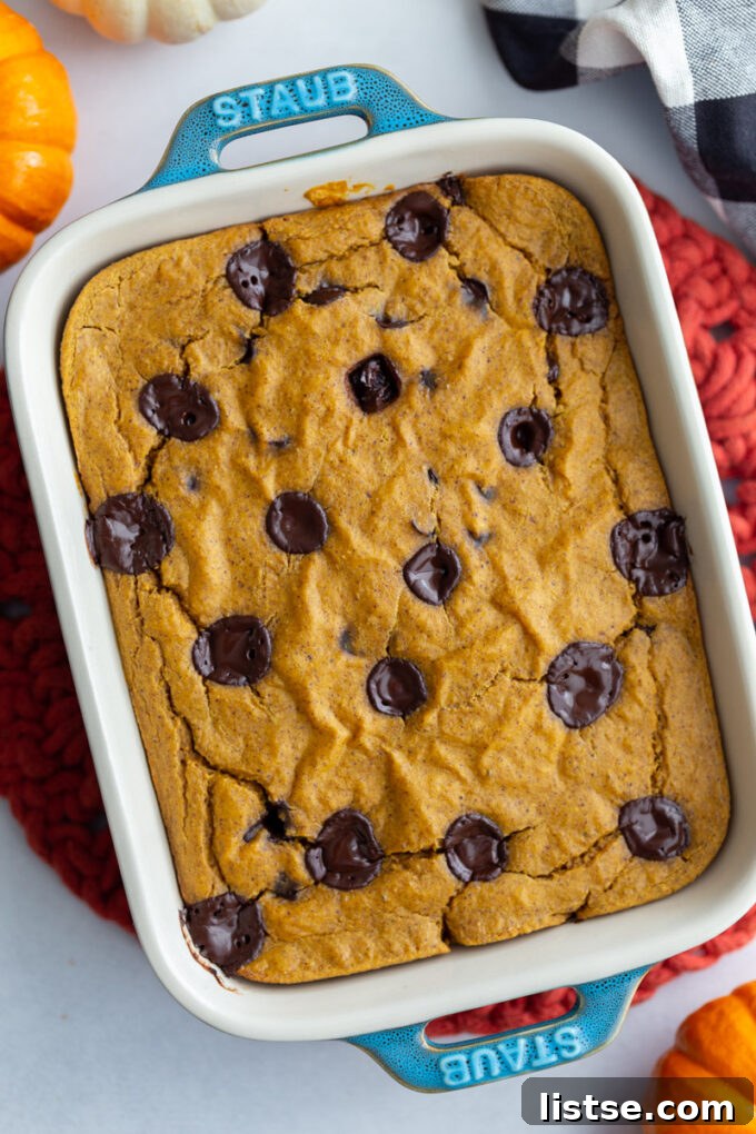 Autumn Spiced Pumpkin Baked Oats 3 A top-down view of a casserole dish filled with pumpkin baked oats, generously topped with chocolate chips, ready to be served.