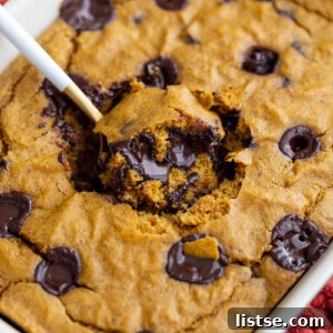 Autumn Spiced Pumpkin Baked Oats 5 pumpkin baked oatmeal with chocolate chunks. A spoonful coming out of the middle of the dish