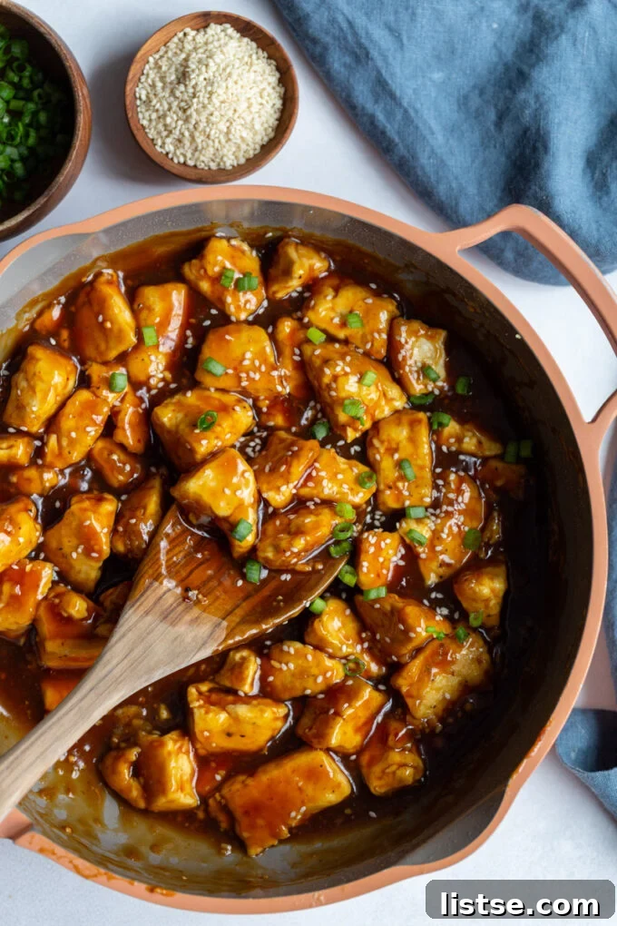 Golden Crispy General Tso Tofu 2 General Tso Tofu in a skillet with a wooden spoon