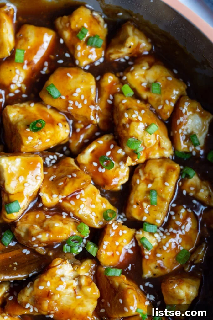 Golden Crispy General Tso Tofu 3 tofu cooked in a sticky sauce in a skillet