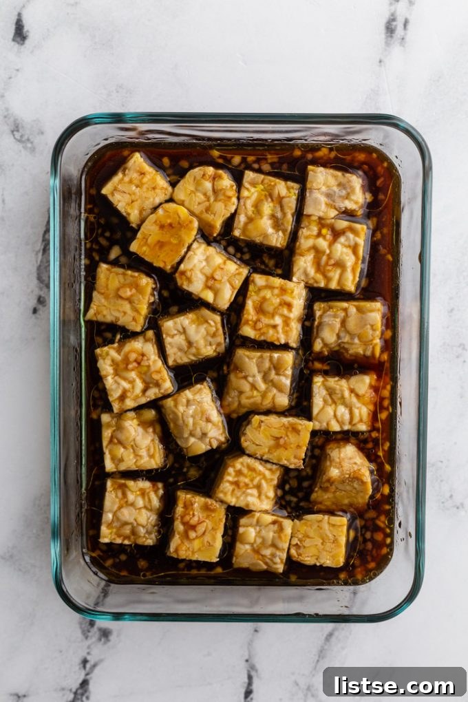 glass container with tempeh marinating in a dark sauce