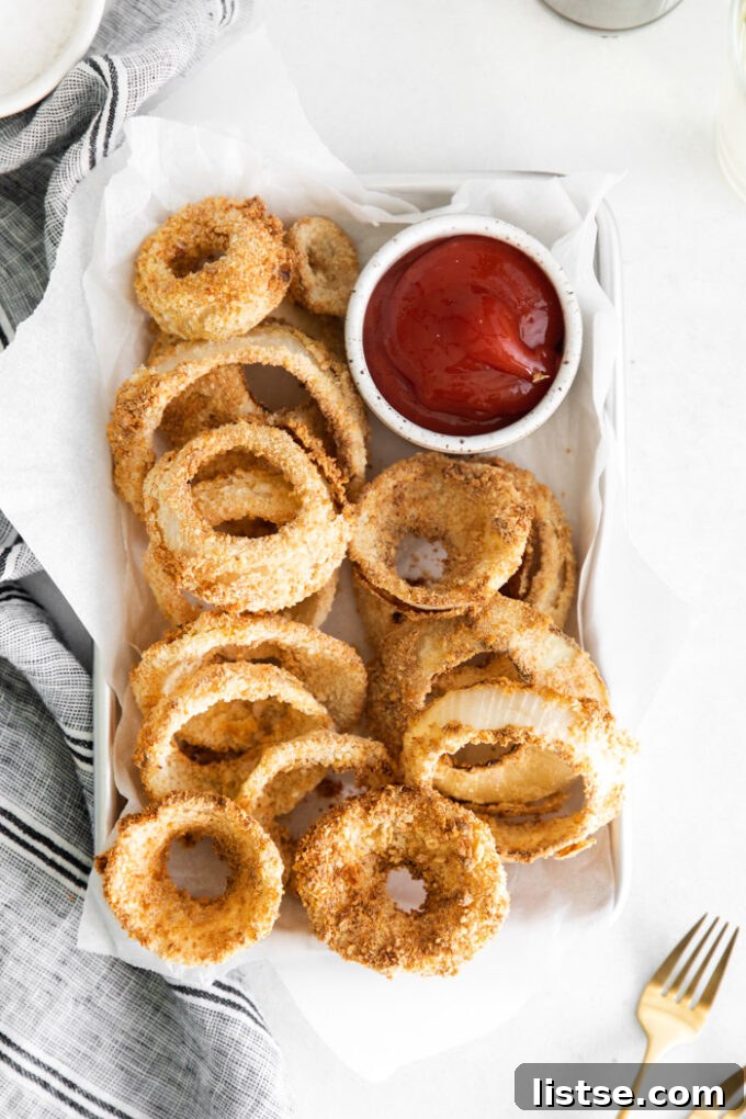 Golden brown crispy onion rings served with a side of vibrant red ketchup.