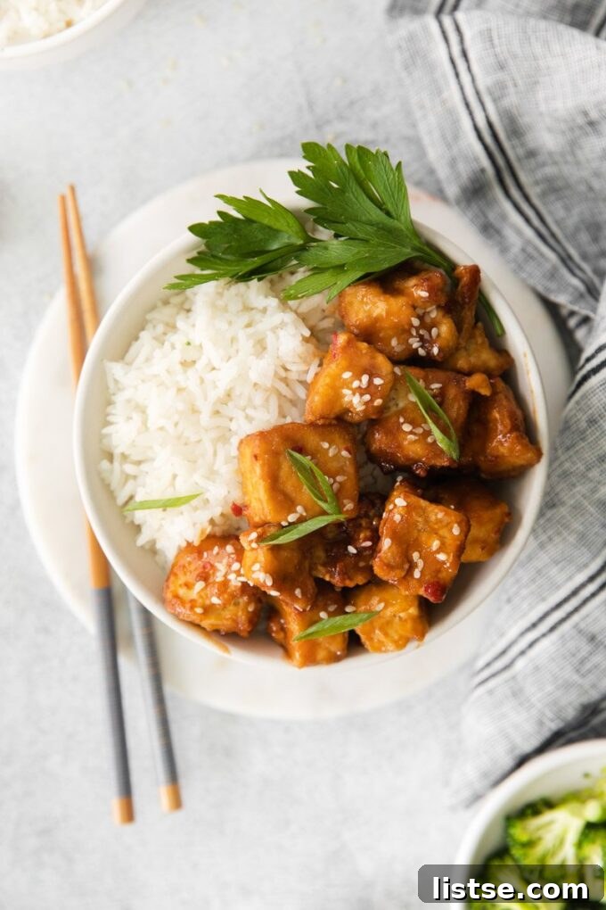Spicy air fryer tofu served elegantly over a bed of fluffy white rice in a small bowl.
