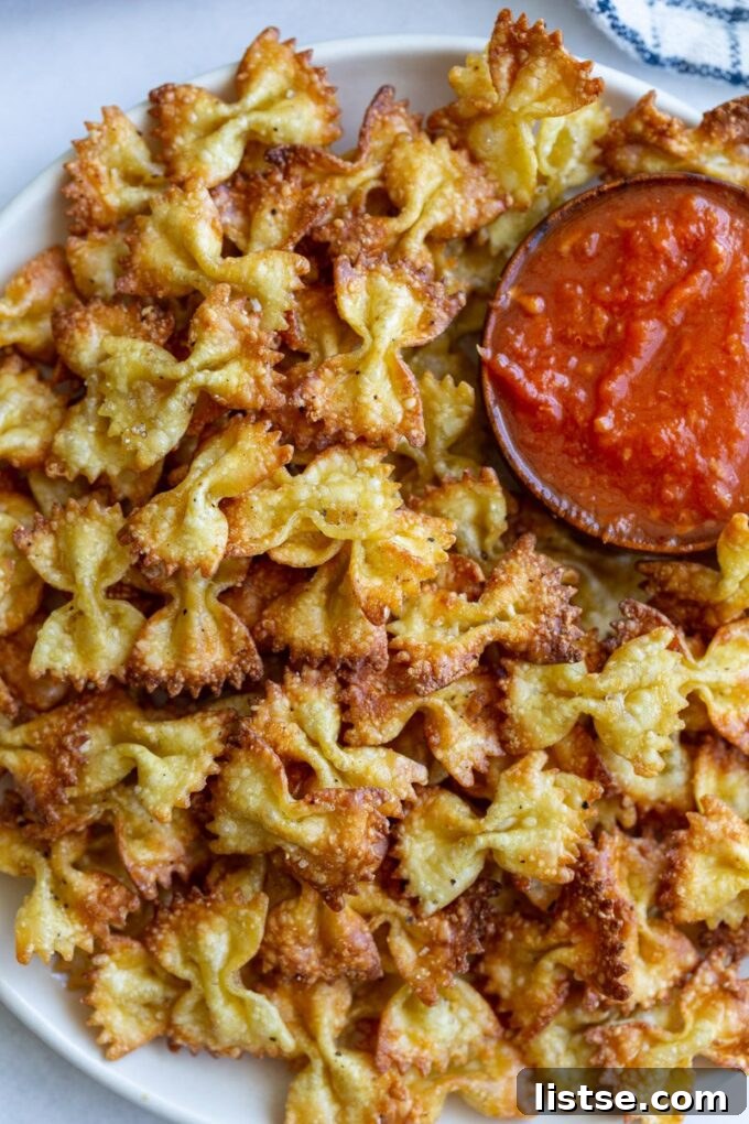 Air fryer pasta chips served in a bowl with a side of rich marinara dipping sauce.
