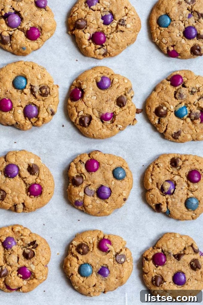 A collection of colorful and fun vegan monster cookies on parchment paper, loaded with mix-ins.