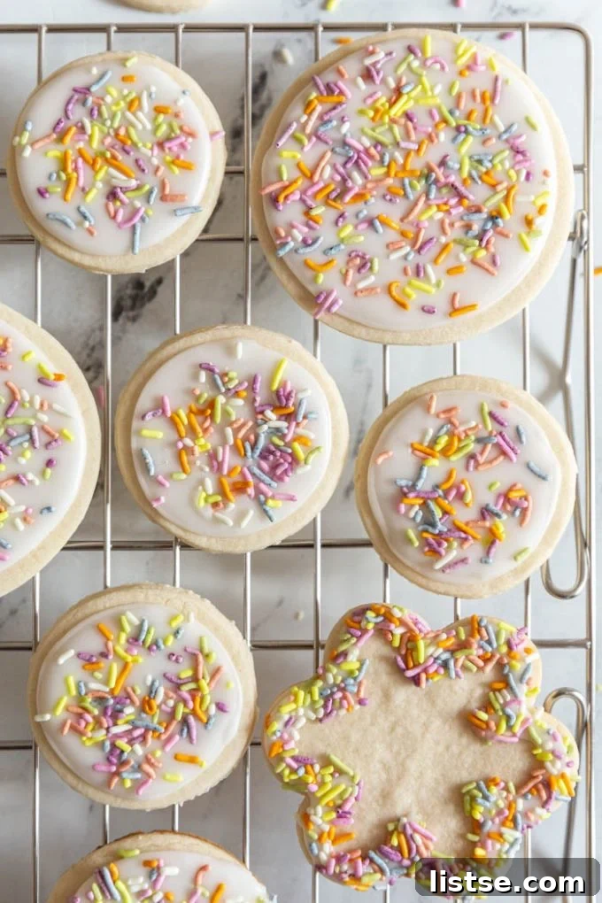 Array of beautifully iced vegan sugar cookies with festive decorations, arranged on a metal cooling rack.