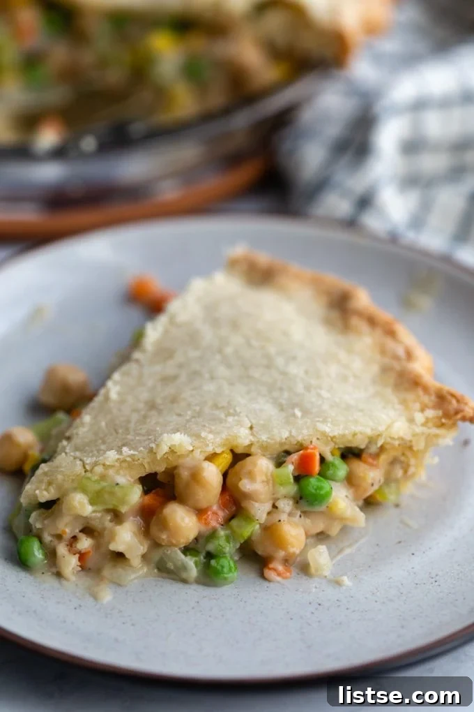 Inspired Chickpea Meals 18 A perfectly portioned slice of chickpea pot pie, revealing a comforting filling of chickpeas and mixed vegetables, with the complete pie visible in the background.