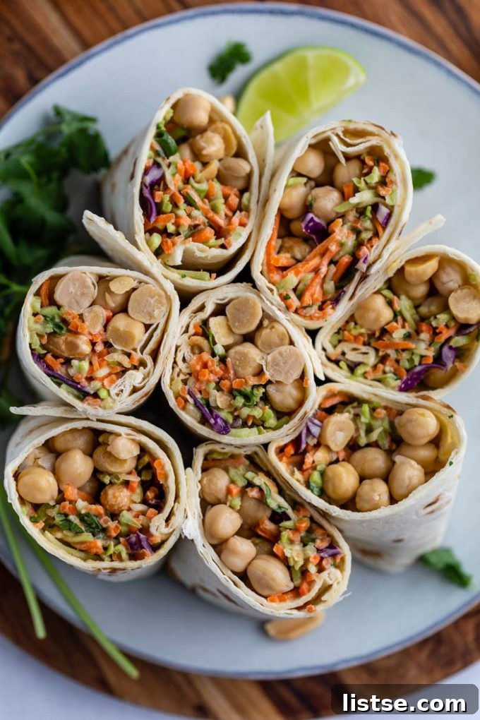 Inspired Chickpea Meals 20 Several tortilla wraps generously filled with a delightful mix of coleslaw and chickpeas, cut in half and standing upright on a plate to reveal their appealing contents.