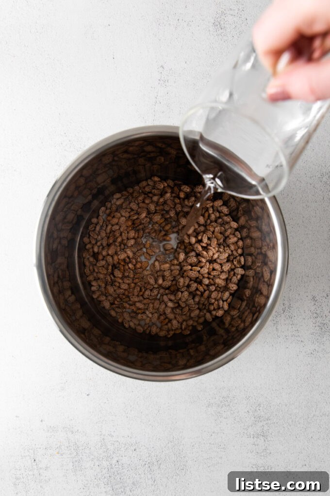 Creamy Instant Pot Pinto Beans 4 Pouring water into an Instant Pot containing pinto beans