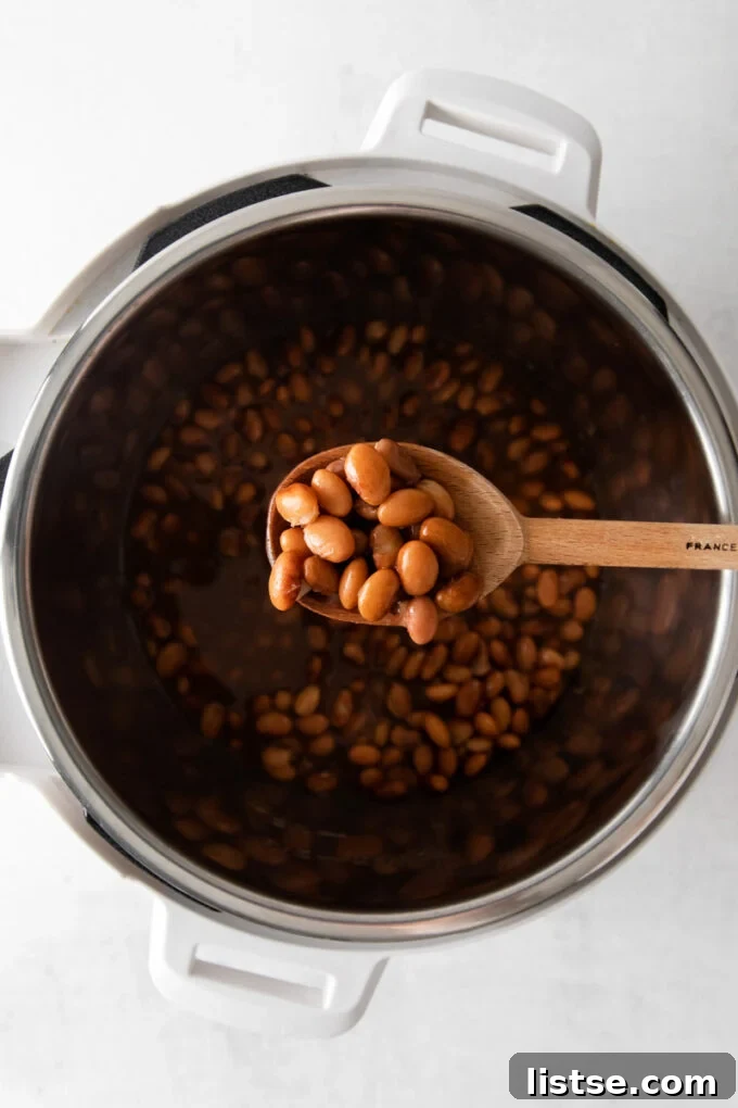 Creamy Instant Pot Pinto Beans 6 Serving pinto beans out of an Instant Pot with a ladle