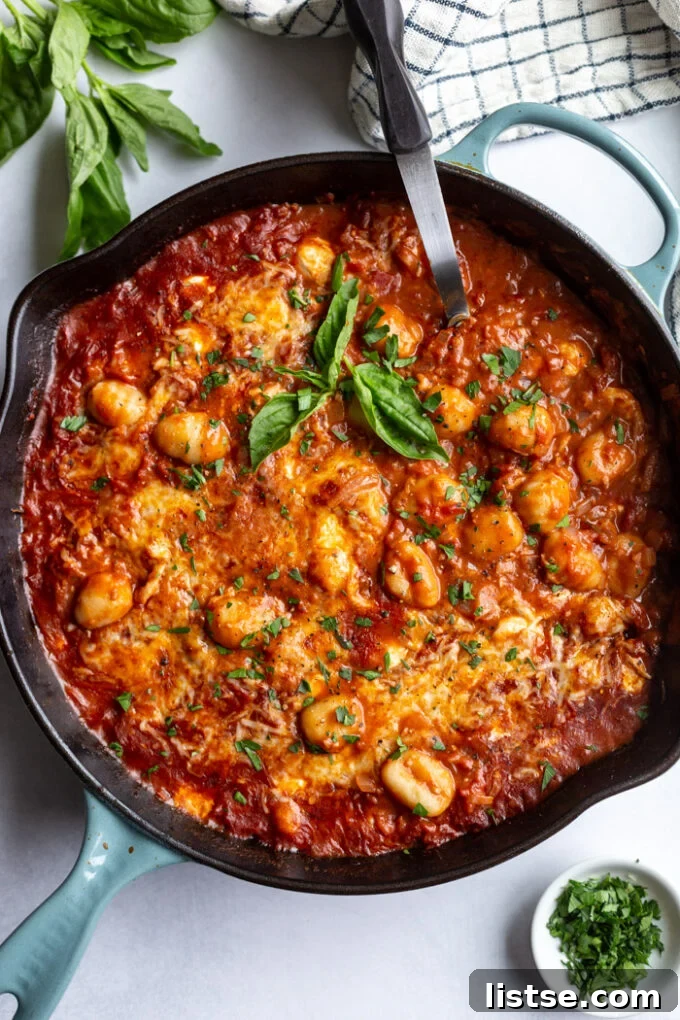 Skillet with gnocchi pomodoro topped with melted cheese and fresh basil