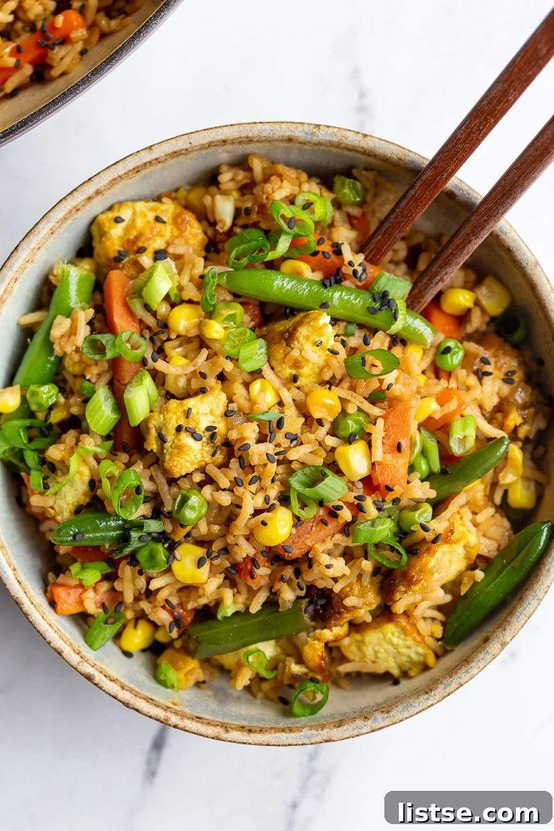 Ultimate Tofu Fried Rice 3 Close-up of Tofu Fried Rice in a small white bowl with chopsticks, showcasing the crispy tofu and colorful vegetables.