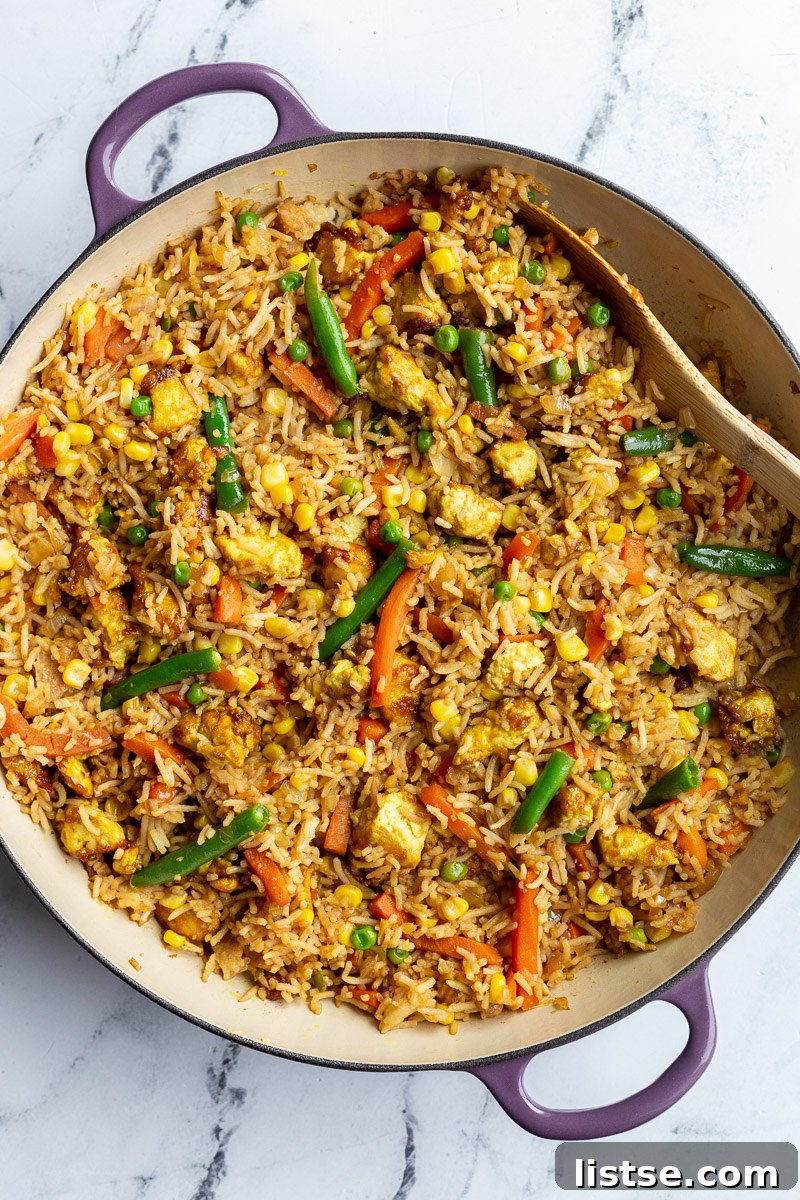 Ultimate Tofu Fried Rice 5 A vibrant close-up of Tofu Fried Rice in a purple skillet, showcasing golden tofu and colorful vegetables.