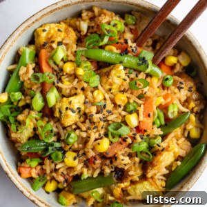 tofu fried rice with veggies in a small bowl with chopsticks sticking out the side