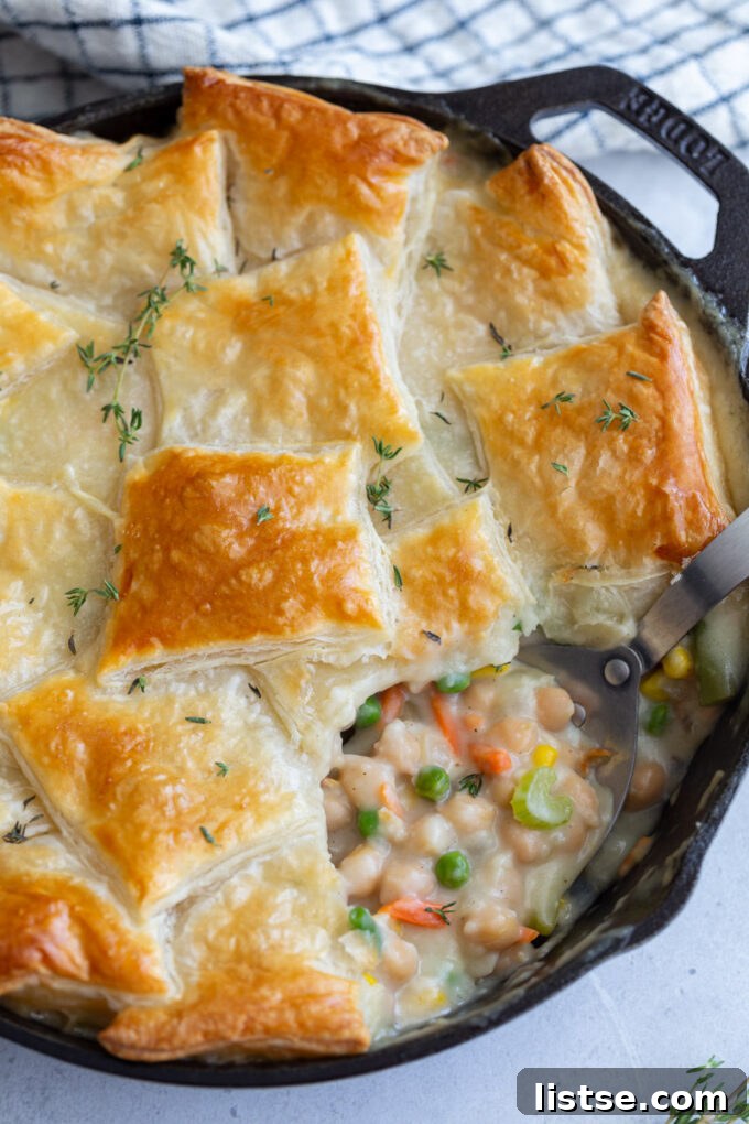 Hearty Chickpea Puff Pastry Pie 5 Serving a generous portion of chickpea puff pastry pot pie from a skillet