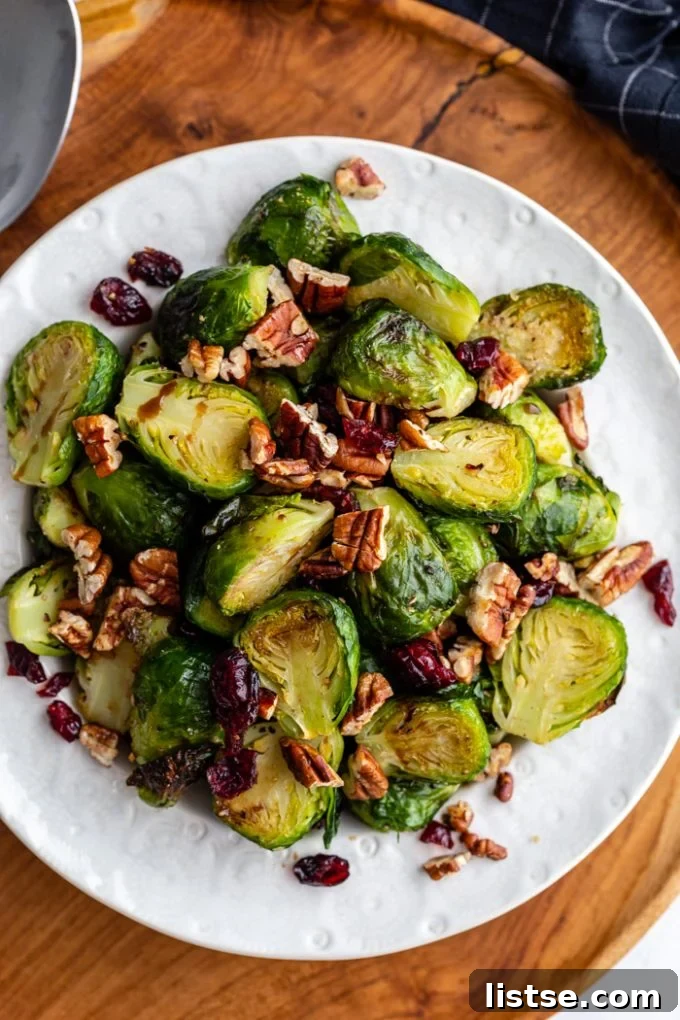 Cranberry Brussels Sprouts on a white plate, garnished with fresh herbs.