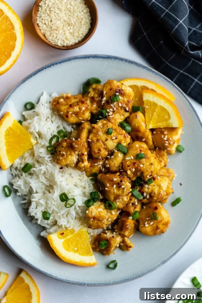 orange tofu served over rice with orange wedges