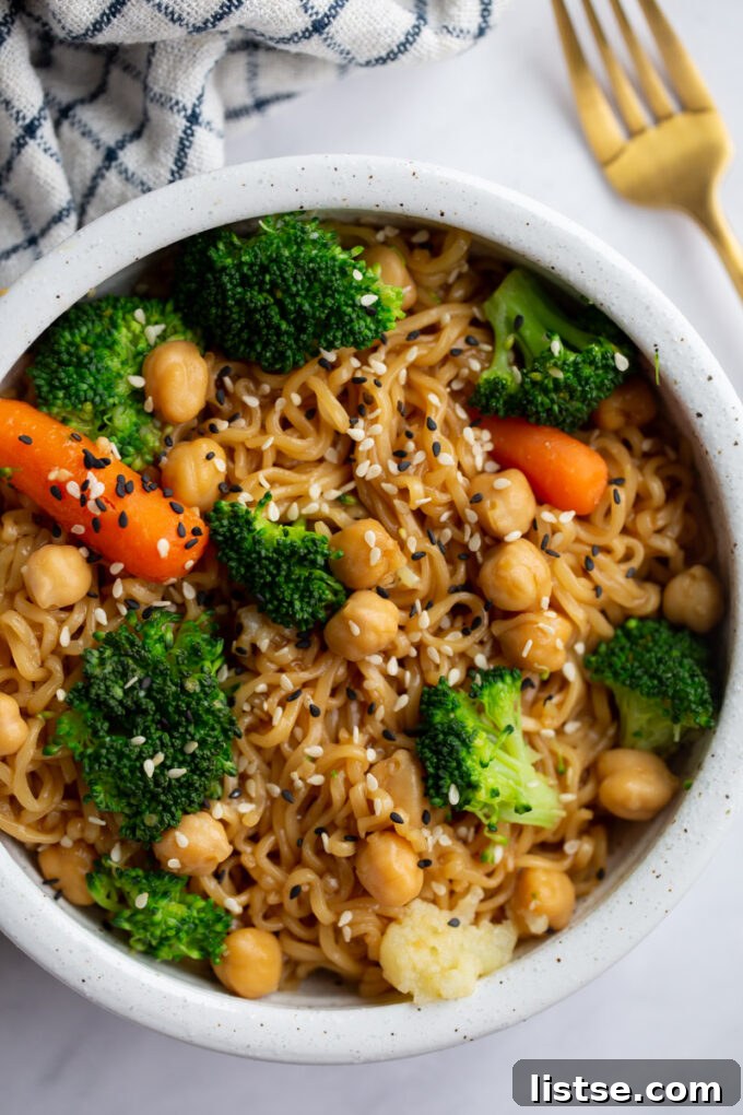 Close-up shot of ramen noodles with a medley of fresh vegetables, including broccoli, sprinkled with sesame seeds