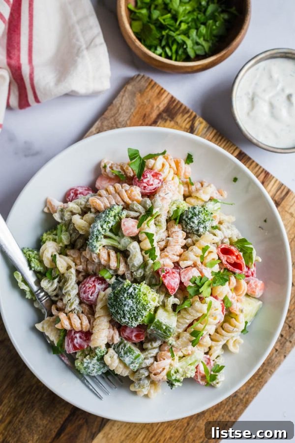 Creamy ranch pasta salad in a white bowl, garnished with fresh herbs