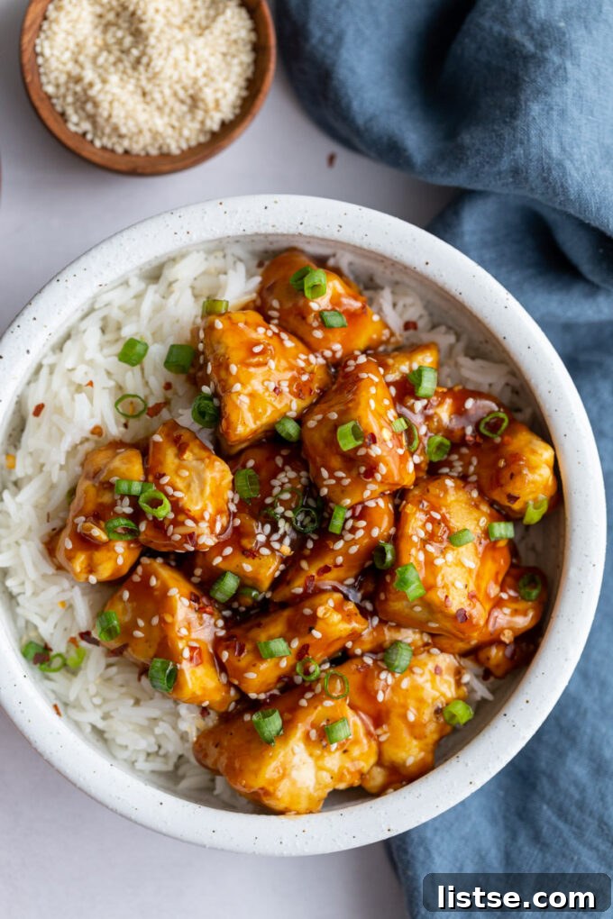General Tso's Tofu served in a bowl with white rice and fresh broccoli