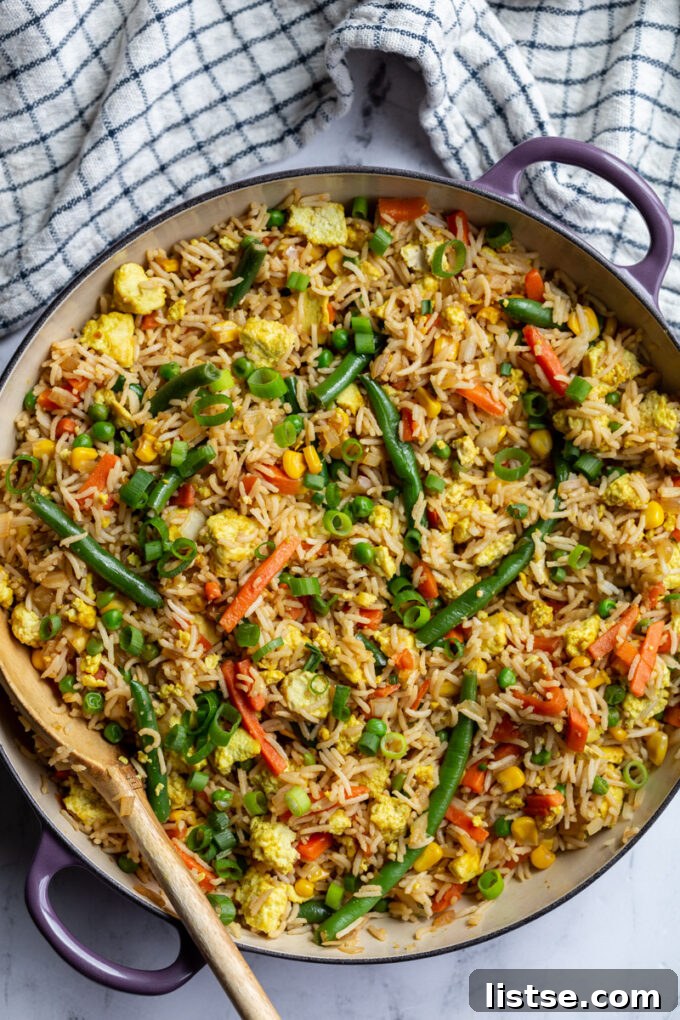 Tofu fried rice cooking in a large skillet, with visible tofu cubes and vegetables like broccoli
