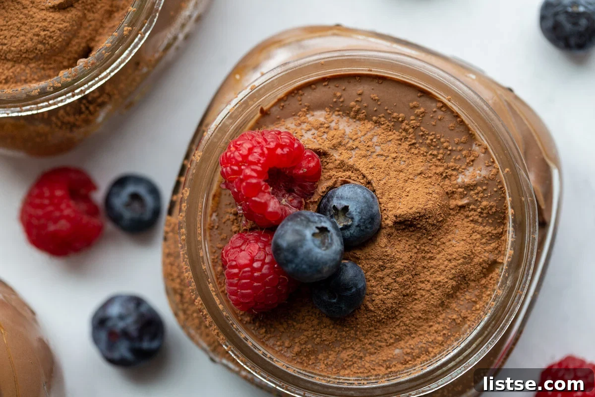 Dreamy Vegan Silken Tofu Chocolate Mousse 3 tofu pudding in a small glass jar with berries, garnished with fresh raspberries and blueberries